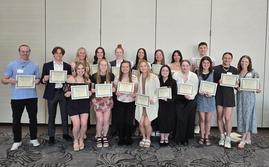 Scholarship recipients stand in a group with their certificates after the SAND banquet.