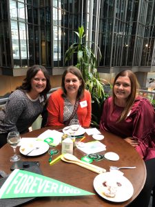 Three alums sit at a table with food and UND swag decorations.