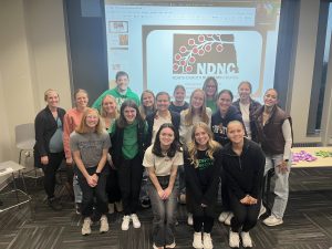 Students gathered in front of a projected image of their logo during a SAND meeting.