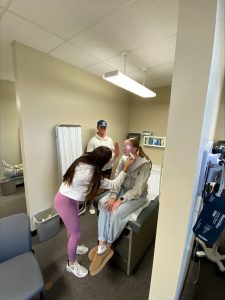 Two N&D students practice a simulation with a live patient in an exam room.