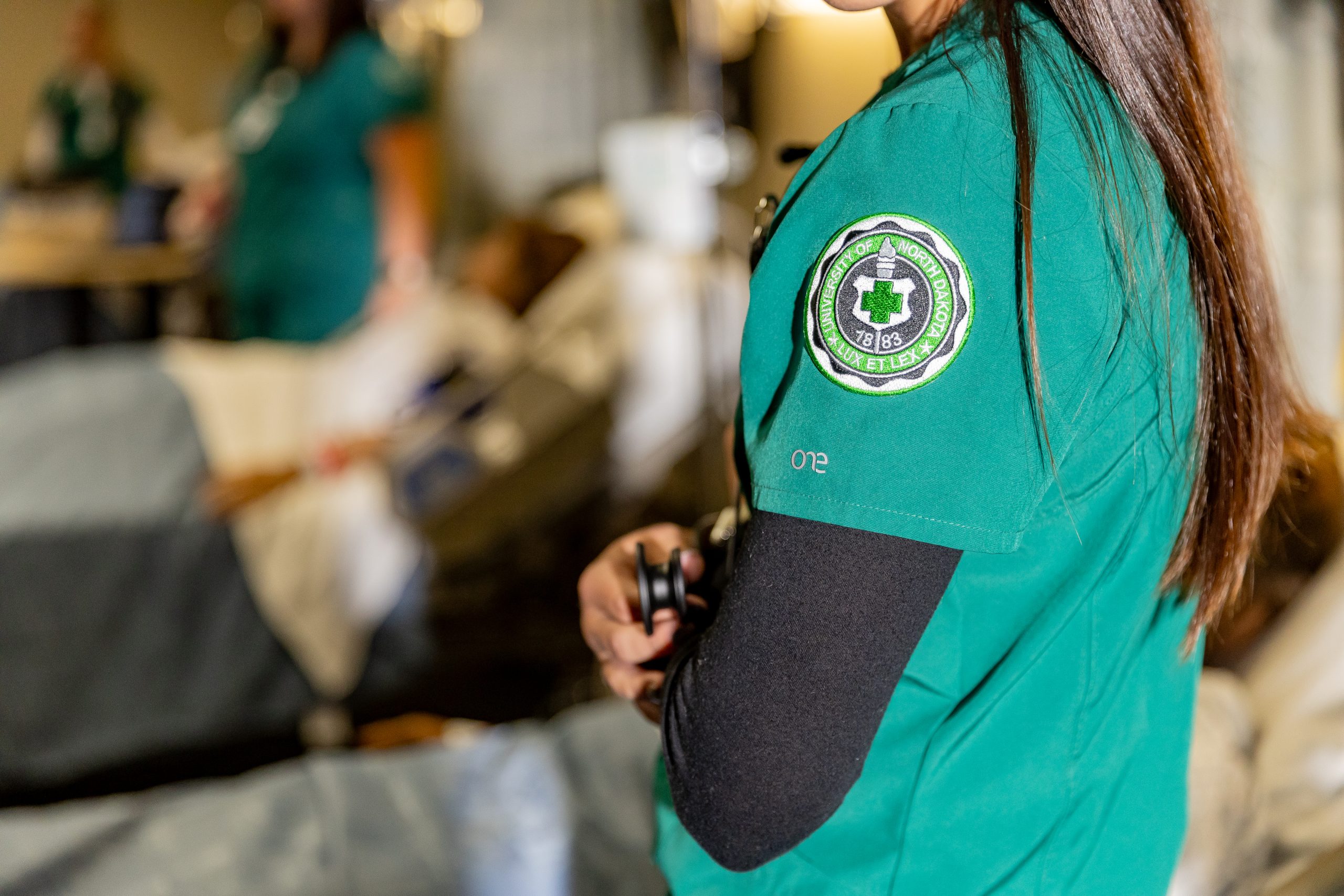 Nurse in green scrubs holding stethescope