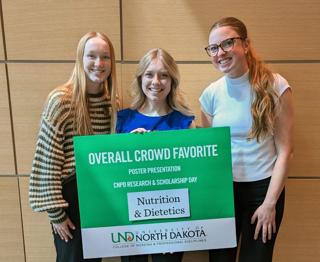 Three students hold a sign that indicates their selection as crowd favorite winners.
