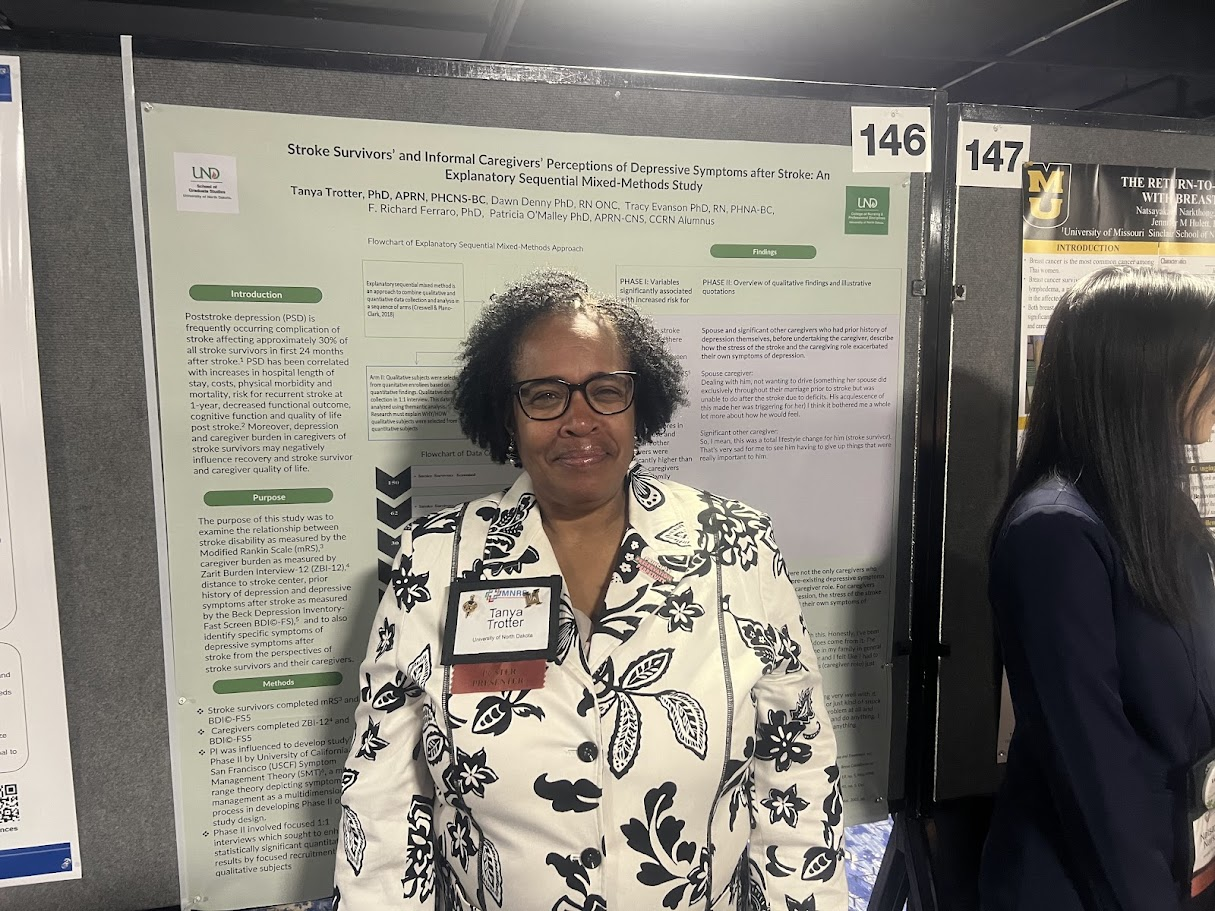 Dr. Tanya Trotter standing in front of her research poster presentation.
