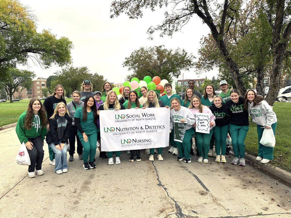 UND CNPD students stand together in front of the parade float holding a sign for the college.