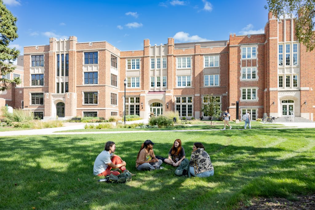 Student sit on the grass on the quad outside of Gillette Hall