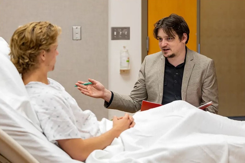 A social worker meets at the bedside of a patient.