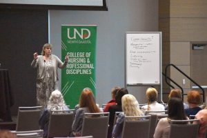Susan Luparell speaks from a stage to a gathered crowd