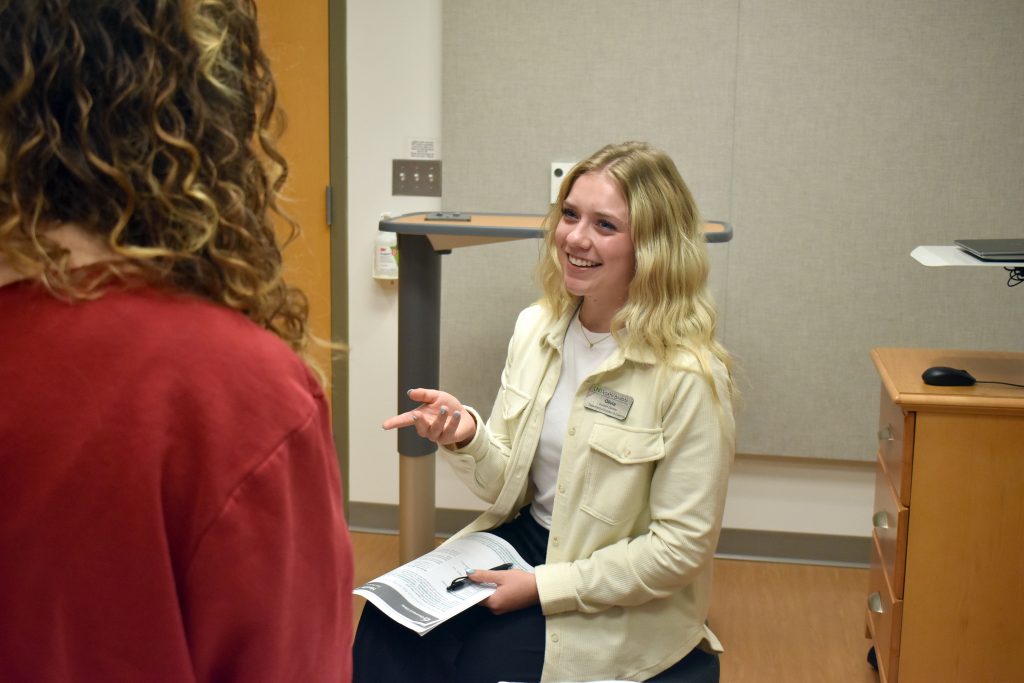 A student visits with a patient in a hospital setting during a simulation exercise