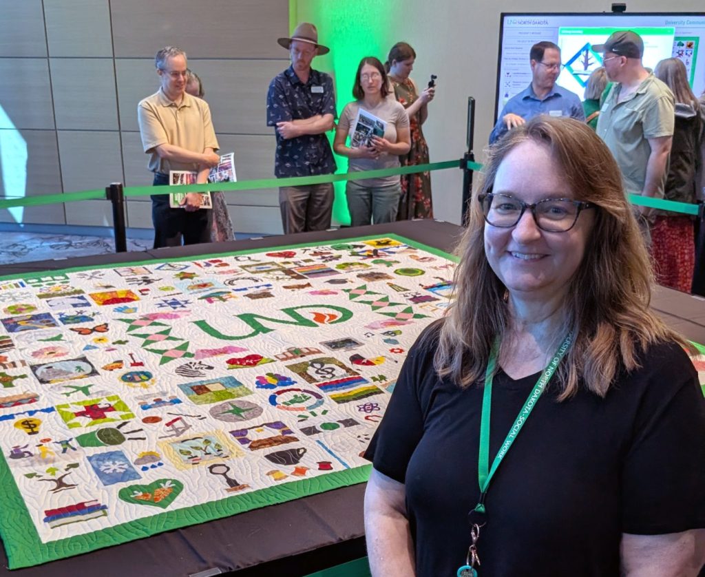 Stephanie Homstad poses with the UND quilt