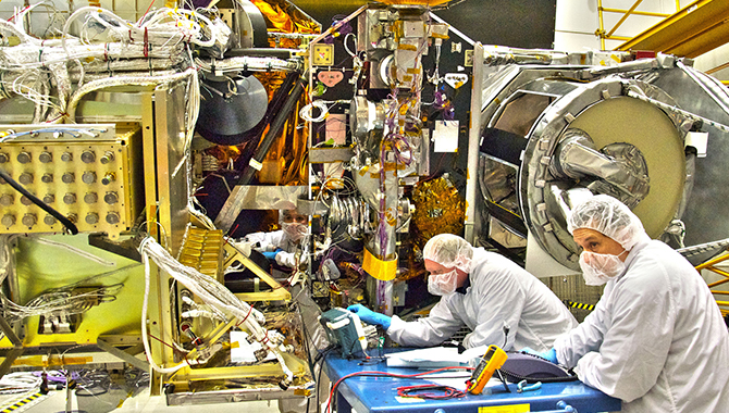 NASA engineers Rob Gallagher (left), Ken Smith (right) and Deneen Ferro (inside the spacecraft, center) work on the GPM Core satellite in the clean room at Goddard Space Flight Center, Greenbelt Md. Credit: NASA