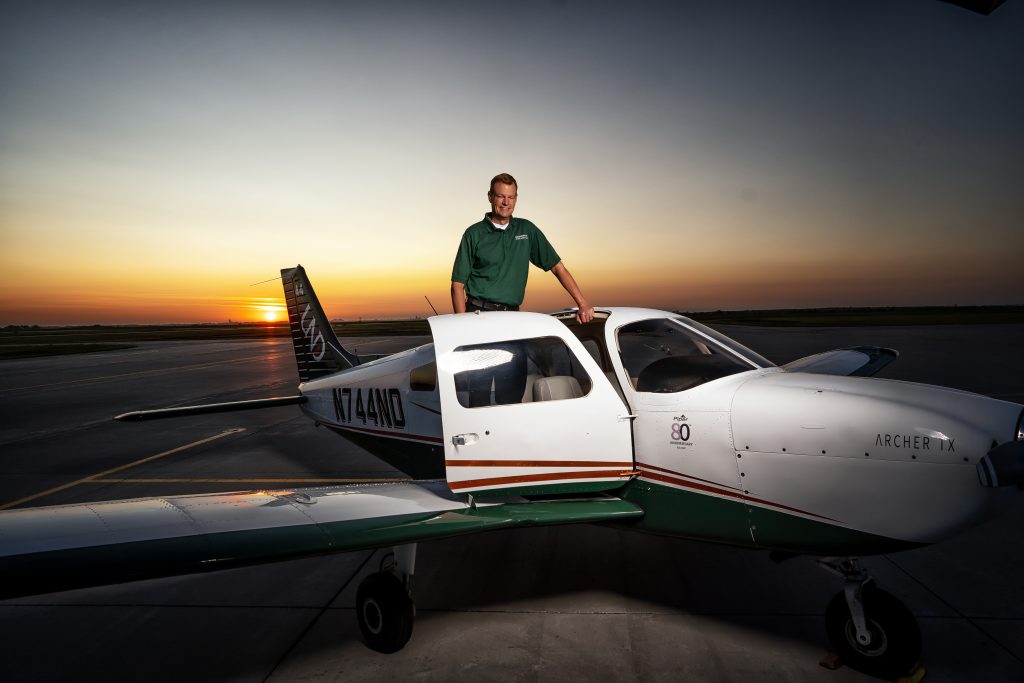 New director of flight operations, Jeremy Roesler, is pictured on the wing of an aircraft smiling.