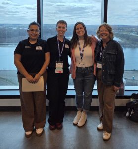 Four women standing side by side posing for a photo.