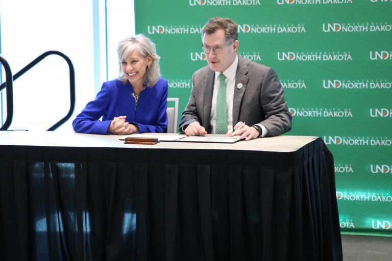 Andrew Armacost sits with Leanne Caret at signing