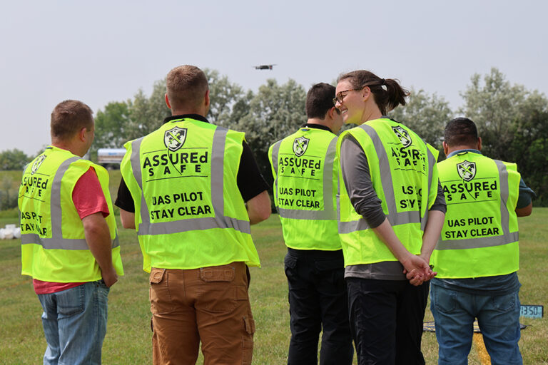 People wearing high-vis vests watching drone in flight