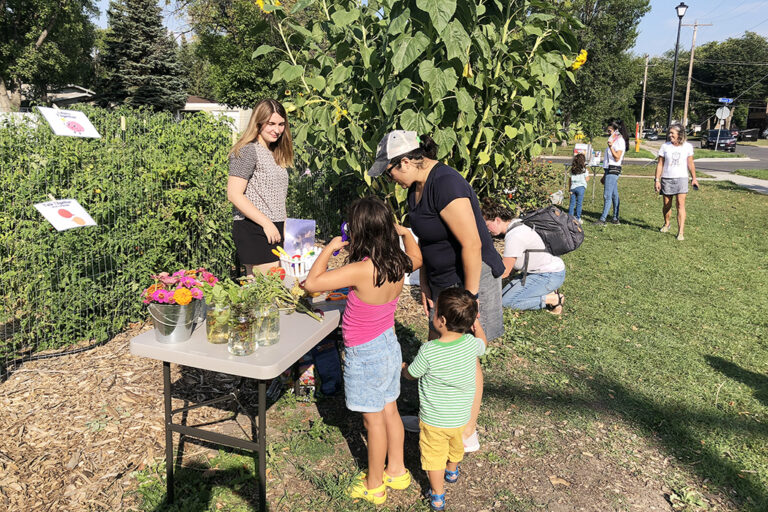 Family looking at displayed flowers and plants on table near garden