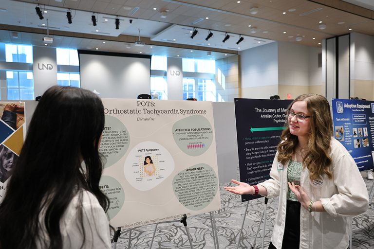 Two people talking next to research poster