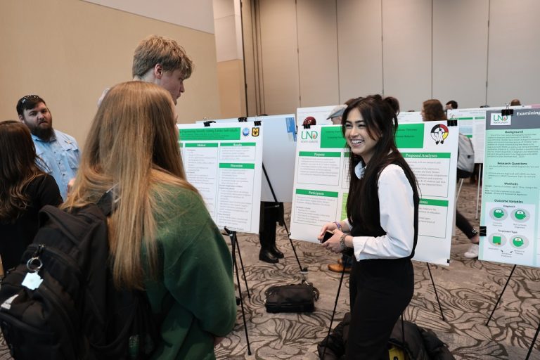 Student presenting research poster at conference