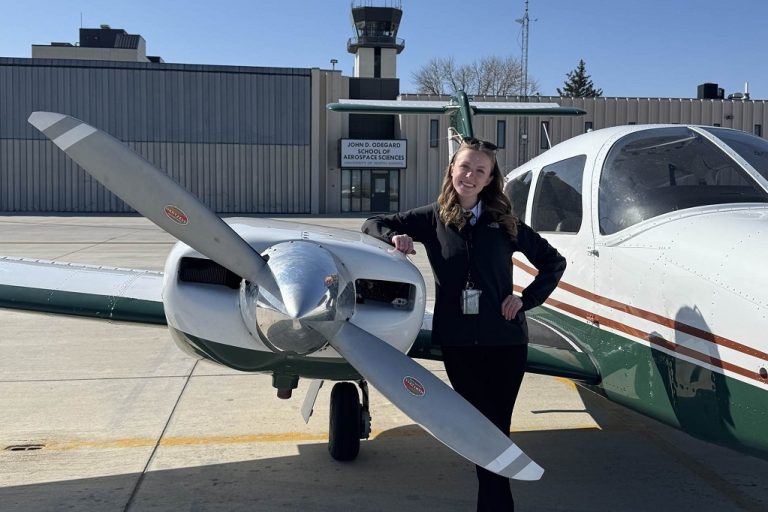 Certified Flight Instructor Sarah Baier, standing alongside a UND aircraft.