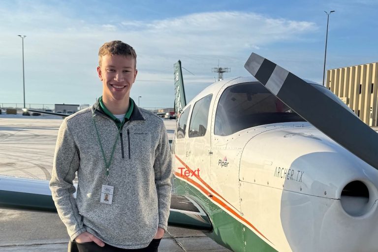Jacob Gutterud stands by a single =engine aircraft