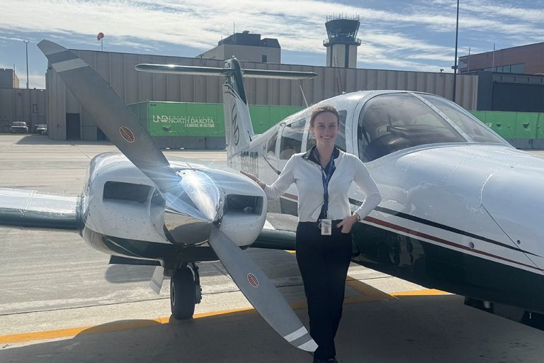 Evelyn Jordan stands beside a UND multiengine aircraft on the flight line at Grand Forks International Airport.