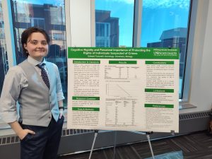 College student standing next to a poster presentation.