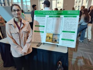 College student standing next to a poster presentation.