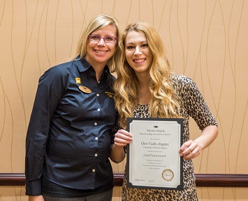 UND chapter president Holly Mitzel (right) receives the Mortar Board Gold Torch from chapter advisor and section coordinator Kristi Okerlund