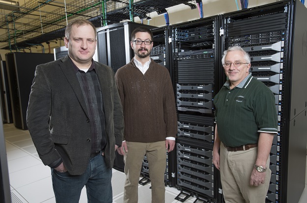 UND Assistant Professor of Computer Sciences Travis Desell (center), along with UND High Performance Computing Specialist Aaron Bergstrom (left) and Ron Marsh, chair of the UND Department of Computer Sciences, gather recently in UND's High Performance Computing facility. Photo by Jackie Lorentz.
