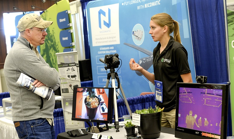 Mechanical engineering Kaci Lemler (right), an employee with Field of View, a UAS-support business, explains how equipment aboard UAS can record and distinguish between living plants and nonliving things. Photo by Jackie Lorentz.