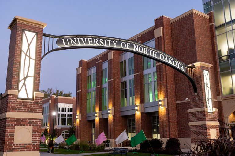 Archway on campus with "University of North Dakota" written across it, Memorial Union in background.