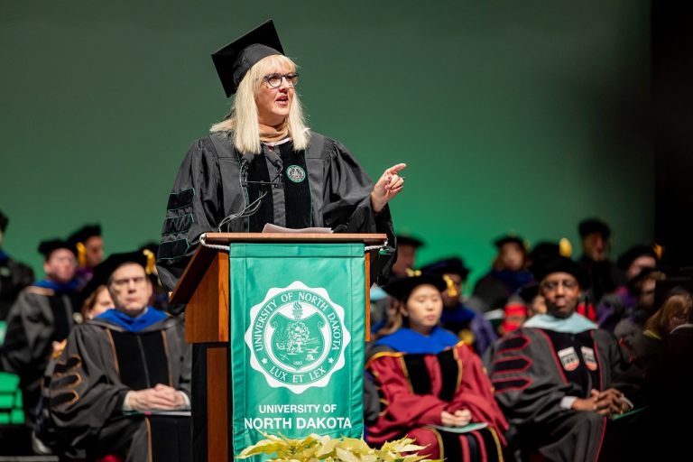 Jill Cholewa standing at podium to address audience at commencement