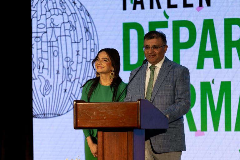 Mohiba and Basir Tareen standing at podium, Basir speaking as Mohiba looks on.