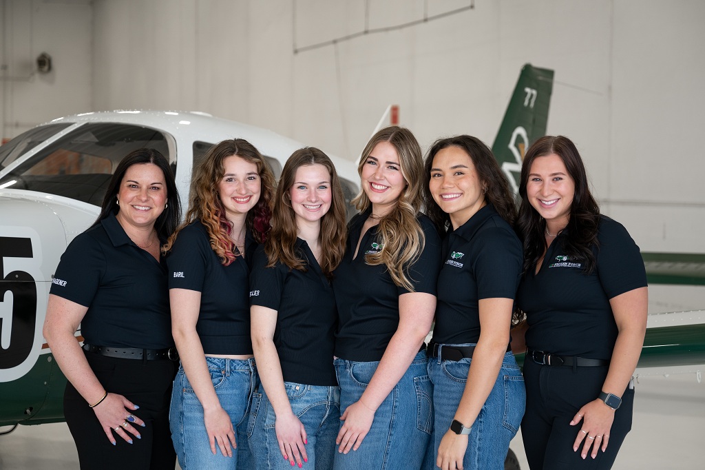 Group photo of Frozen Force Air Race Team, standing in front of plane in hangar