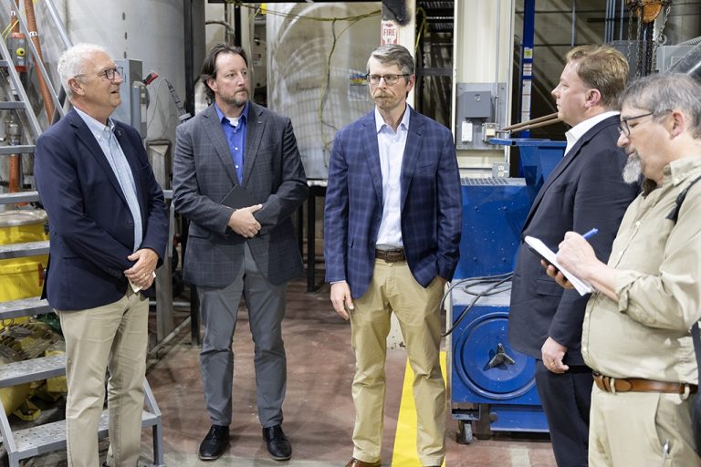 Kevin Cramer, David Straley, Dan Laudal and Michael Duffey stand in conversation, person in foreground taking notes
