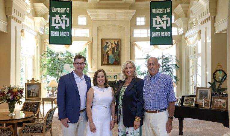 With UND banners in the background, (from left) President Andy Armacost, First Lady Kathy Armacost, Paula Trom and B. John Barry stand together on the occasion of Barry being awarded the UND President’s Medal. Through his charity work and The Barry Foundation, which he established, “John impacts the world, the region, and UND,” the citation for the medal reads. UND Alumni Association & Foundation photo.