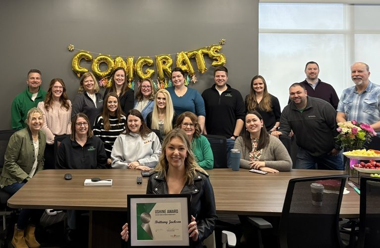 Brittany Jackson holding certificate with colleagues gathered behind