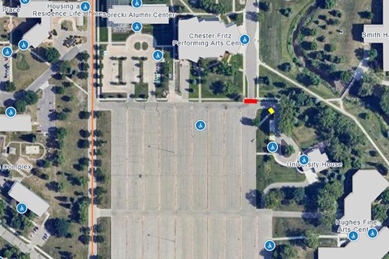 Overview of Chester Fritz Performing Arts Center Parking lot shows red lines over blocked entry points, yellow lines at closed sidewalks to south and north east of lot, as well as orange arrows along roads near the lot to show traffic routes.