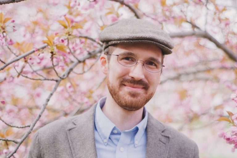Patrick Henry standing in front of background of pink blossoms on trees