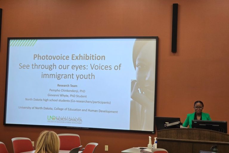 Person standing at lectern next to projected presentation