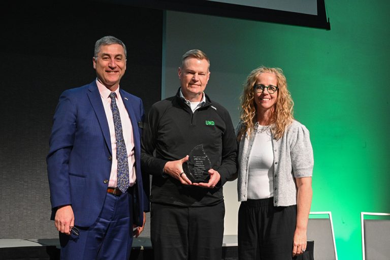 Jeremy Roesler at center holding award between Bob Kraus and Karla Mongeon-Stewart
