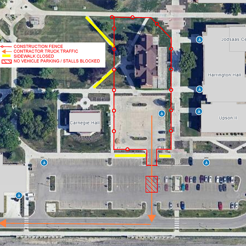 Overview of demolition site and nearby parking lots. Red line marks work site, yellow lines mark closed sidewalks and hashed section south of work site marks closed parking stalls. Orange arrows show flow of construction-related traffic.