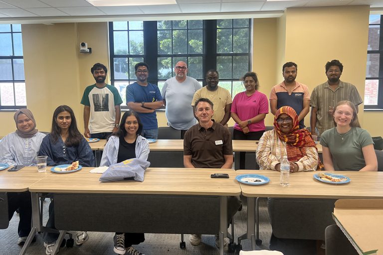Students gathered with faculty advisors for group photo at pizza party