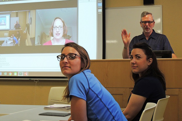Bailey Kitko (left) and Bridget Hill, Social Work students at UND, listen to Bruce Reeves (at podium), a UND Social Work faculty member, and Melissa Gjellstad (on screen from Norway), UND associate professor of Norwegian, discuss life in Scandinavia during an orientation session in preparation for Kitko and Hill's internship in Sweden.