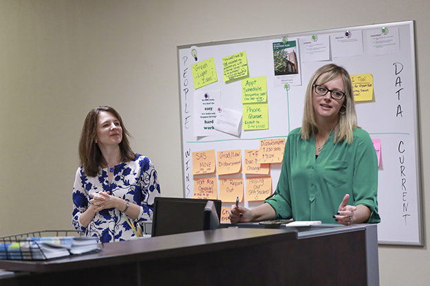 Director of Student Financial Aid Janelle Kilgore, right and Student Account Operations Mgr. Chelsea Larson, left talk with a large team about student financial aid. (Jackie Lorentz photo/ UND Today)