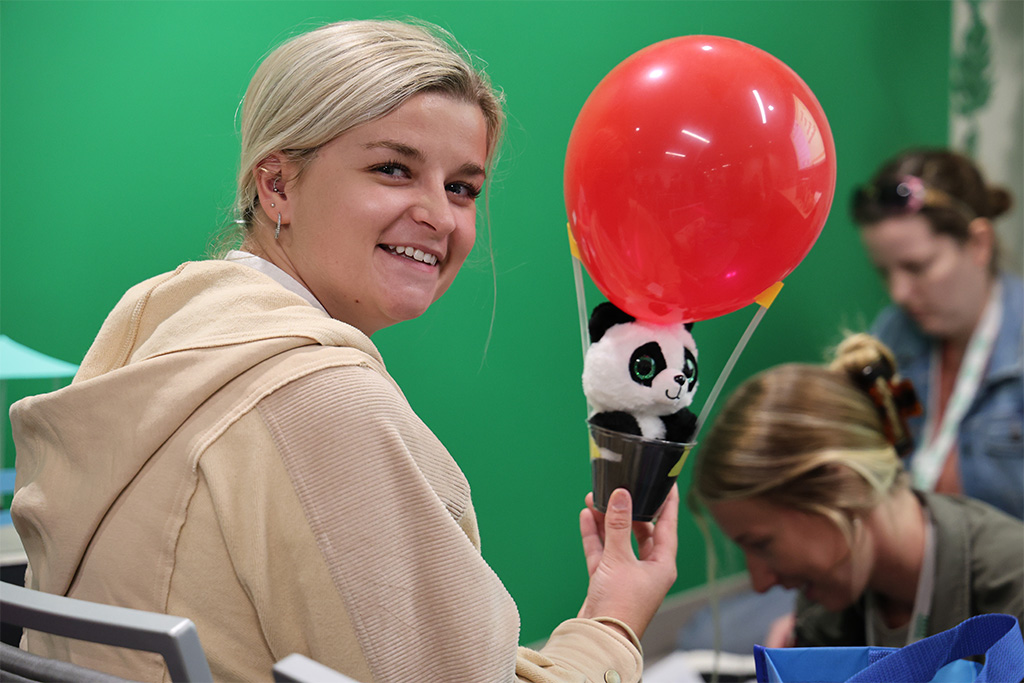 teacher holds panda in devive made from a cup, straws and balloon