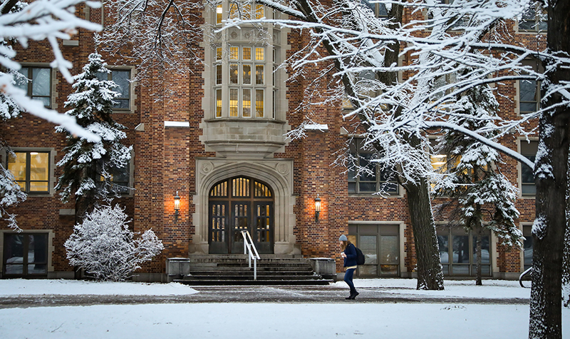 Student walking past Merrifield Hall in winter