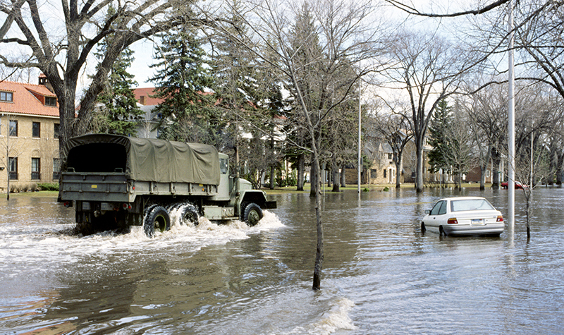 Covered army truck drives through flooded streets