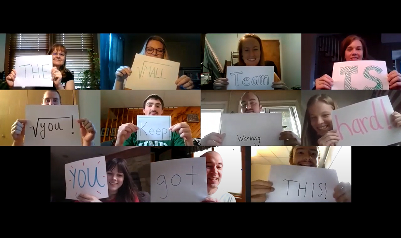 Zoom screenshot of people holding up paper signs