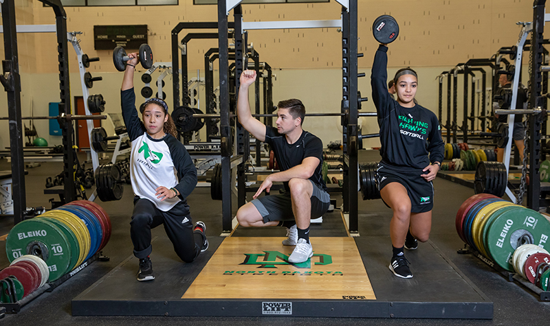 Student athletes perform guided weight exercises
