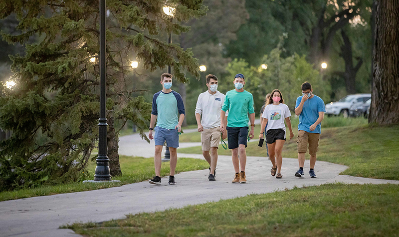 Students wearing masks walk on campus